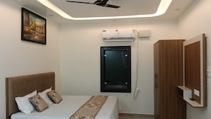 Ein Hotelzimmer mit einem Bett, einem Deckenventilator, einer Klimaanlage, einer Tür und einem Holzschrank.
