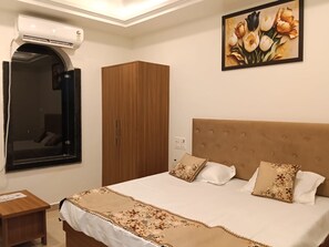 A bedroom with a bed, a wardrobe, a mirror, and a wall-mounted air conditioning unit. - RS Resort (Tahrauli)