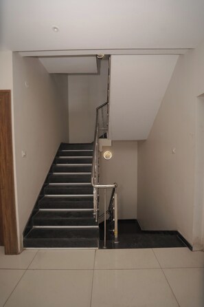 Una escalera con barandilla metálica y una lámpara colgante.
