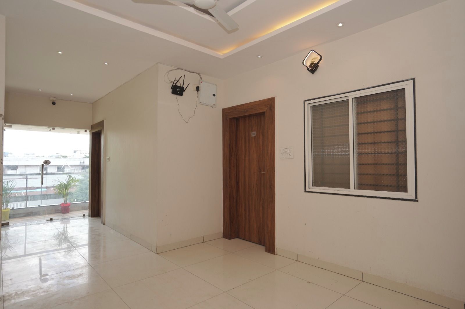 Una habitación amplia con un ventanal grande, una puerta de madera y un ventilador de techo.