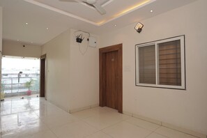Una habitación amplia con un ventanal grande, una puerta de madera y un ventilador de techo.
