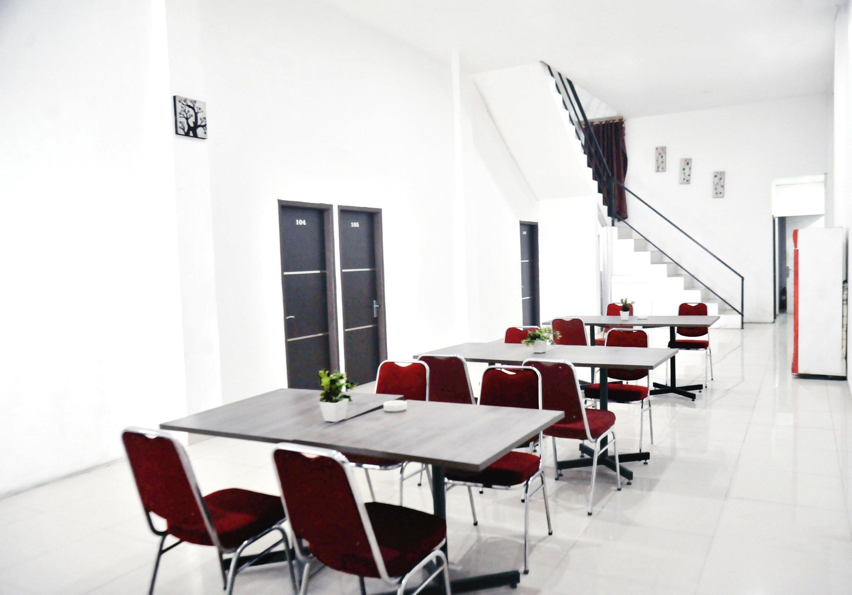 A modern conference room with white walls, black doors, and red chairs.