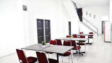 A modern conference room with white walls, black doors, and red chairs.