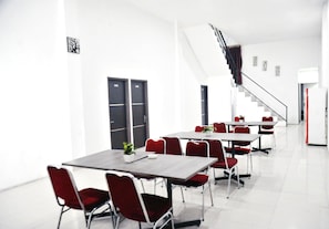 Une salle de conférence moderne avec des murs blancs, des portes noires et des chaises rouges.