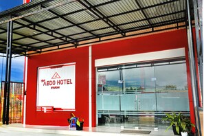 Un hôtel avec une façade rouge, une grande enseigne et une entrée abritée.