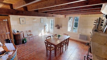 Un coin repas rustique avec une table et des chaises en bois, un sol en briques et un mur en pierre.