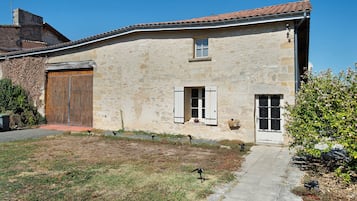 Un bâtiment rustique en pierre, avec un toit en tuiles, une porte en bois et une petite fenêtre avec des volets.