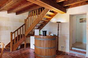 A wooden staircase with a metal railing, a wooden barrel, and a wall-mounted sign listing wine varieties.