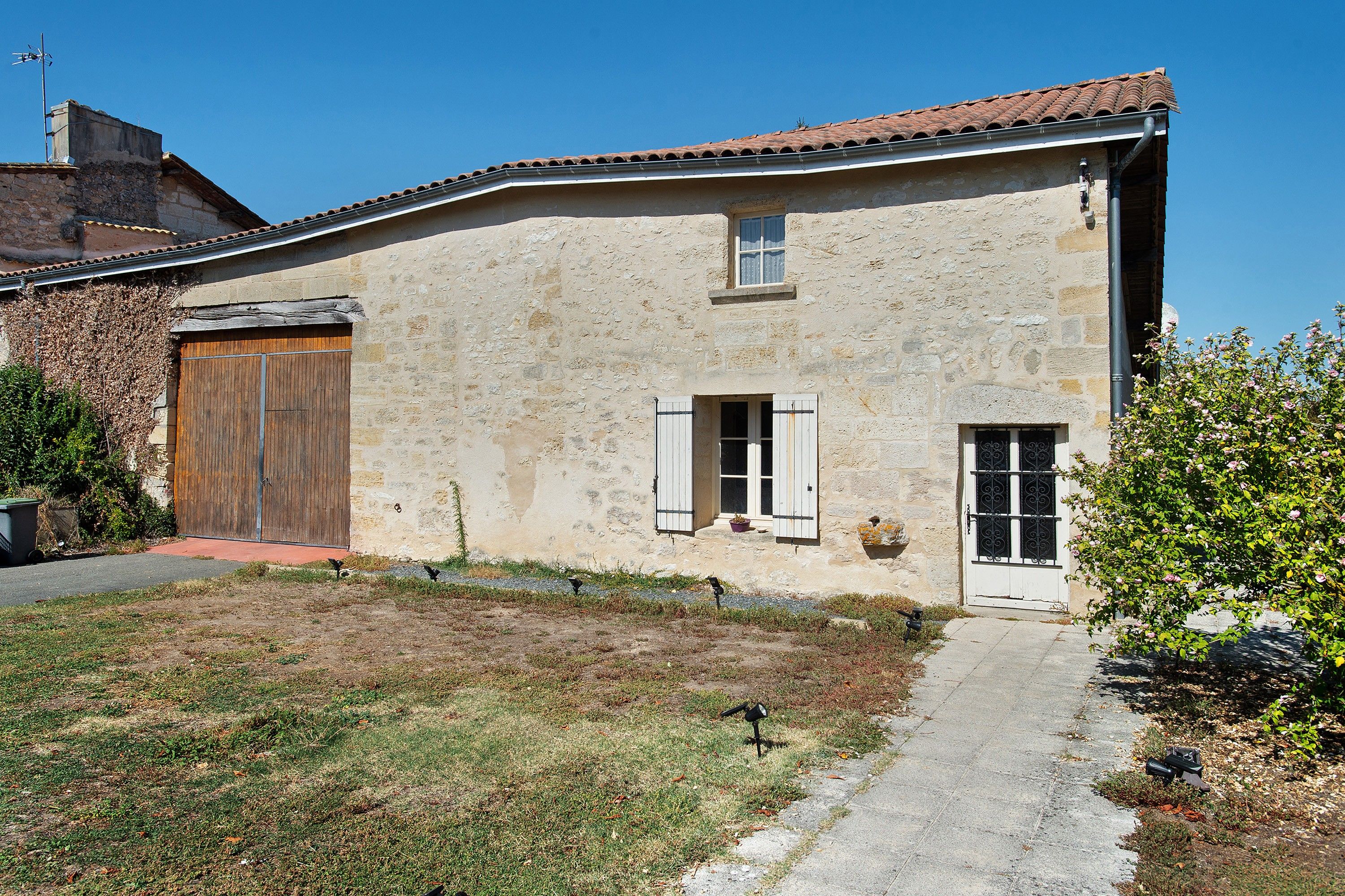Un bâtiment rustique en pierre, avec un toit en tuiles, une porte en bois et une petite fenêtre avec des volets.