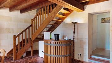 A wooden staircase with a metal railing, a wooden barrel, and a wall-mounted sign listing wine varieties.