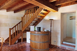 Un escalier en bois avec une rampe en métal, un tonneau en bois et une enseigne fixée au mur indiquant les différentes variétés de vin.