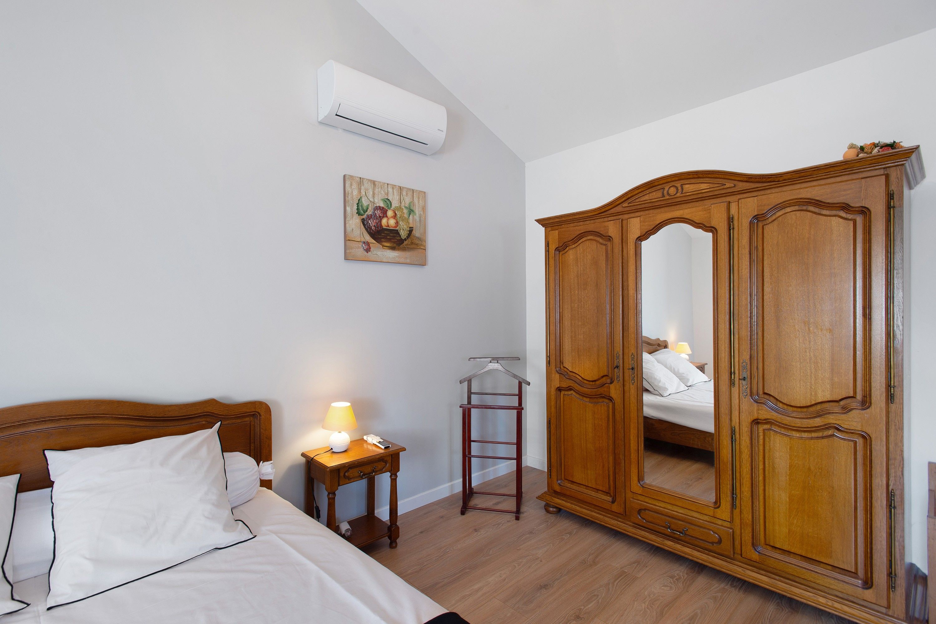 Une chambre à coucher comprenant un lit, une armoire, une table de chevet et un appareil de climatisation.