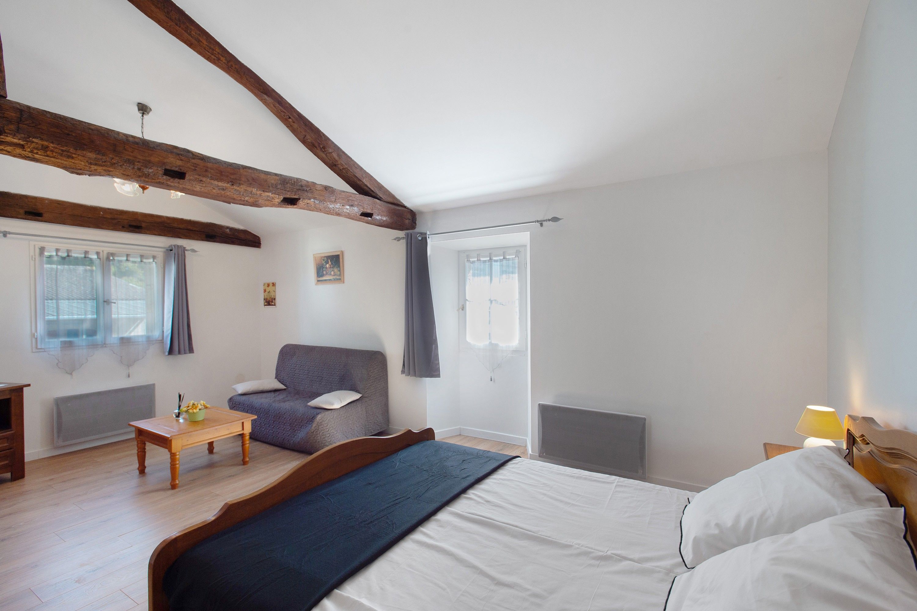 Une chambre à coucher avec un lit, une chaise, une table et une fenêtre.