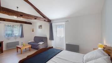 Une chambre à coucher avec un lit, une chaise, une table et une fenêtre.