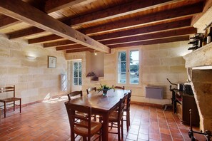 A rustic dining area with a wooden table, chairs, and a stone wall.