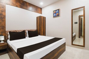 A hotel room with a large bed, a nightstand, a mirror, and a wall-mounted artwork. - Hotel O Jamshedpur Near Burma Mines (Golmuri)