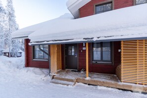 A red wooden cabin with a snow-covered roof and a wooden porch. - SointuiLevi Premium A71 by Holiday in Lapland (Levi)