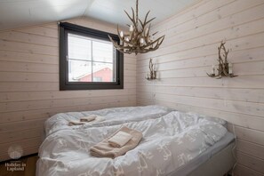 A room with a bed, a chandelier, and a window with blinds. - SointuiLevi Premium A43 by Holiday in Lapland (Levi)