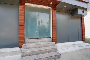 A modern building entrance with a glass door, wooden accents, and a set of concrete steps leading up to it. - Collection O Gomti Nagar Near Amity (Lucknow)