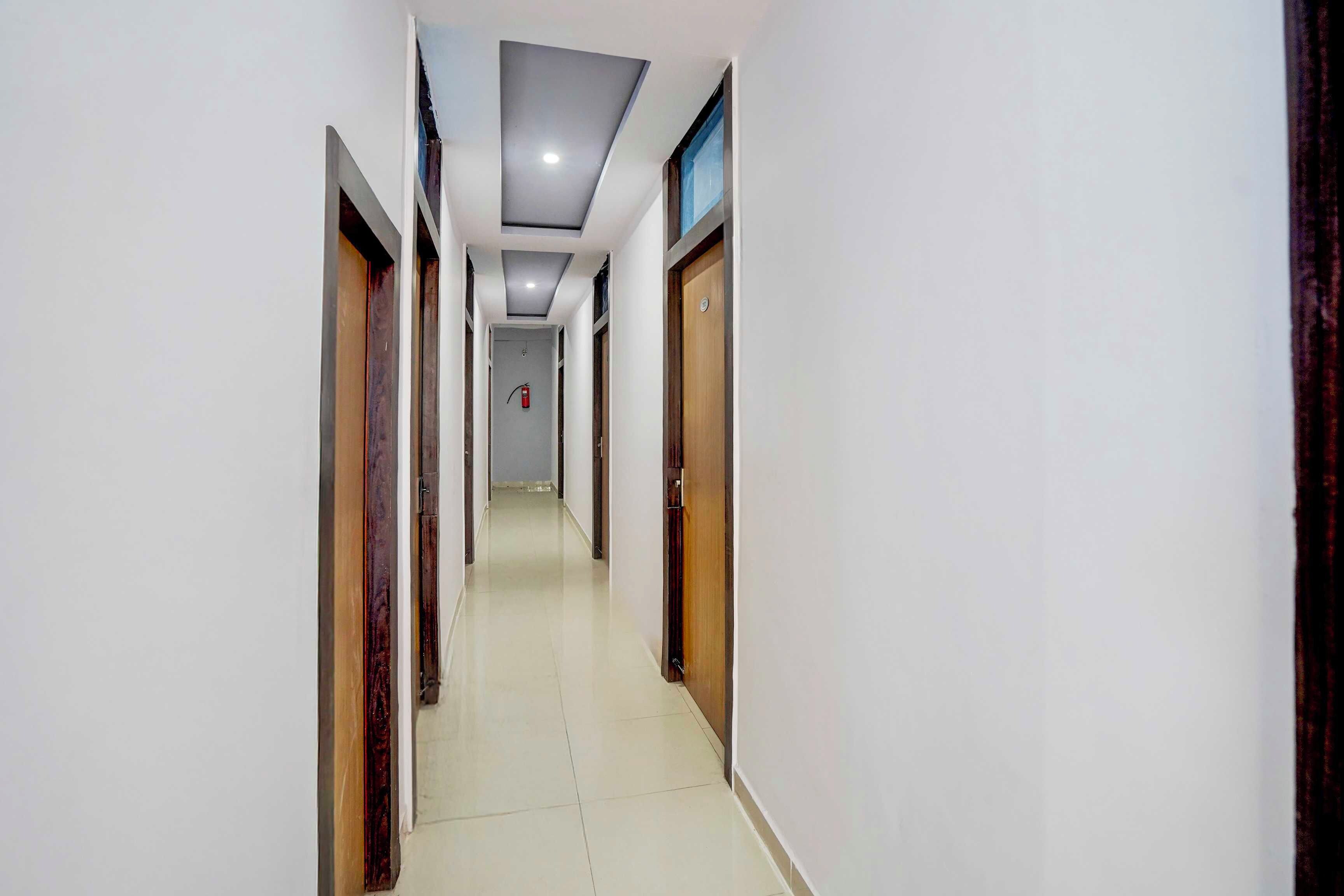 A corridor with doors on both sides, a tiled floor, and a ceiling with recessed lighting.