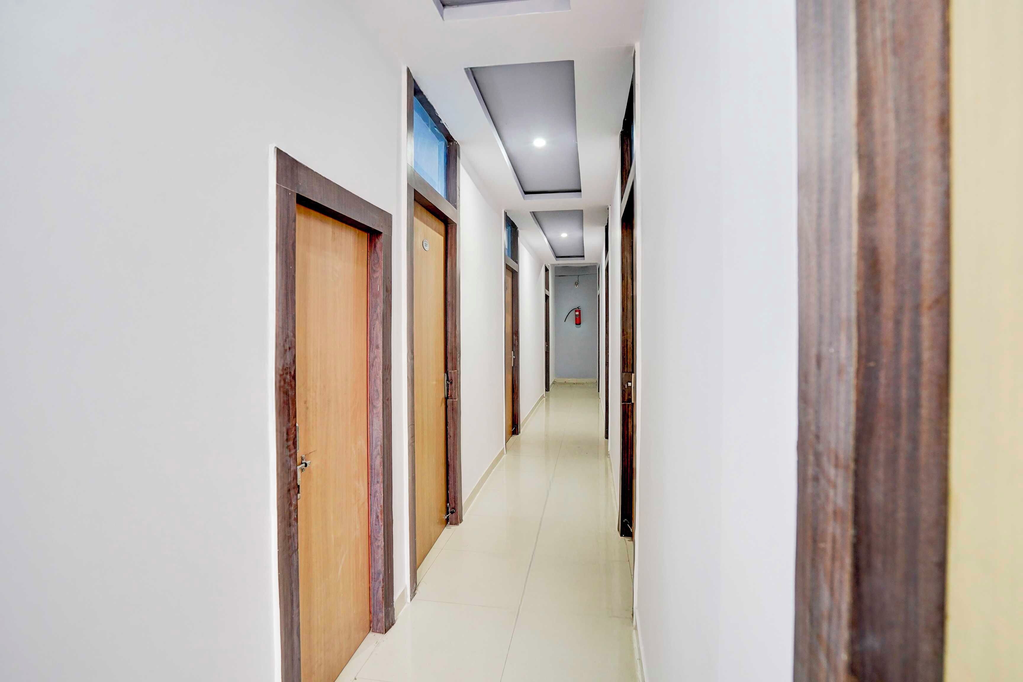 A corridor with wooden doors and a fire extinguisher mounted on the wall.