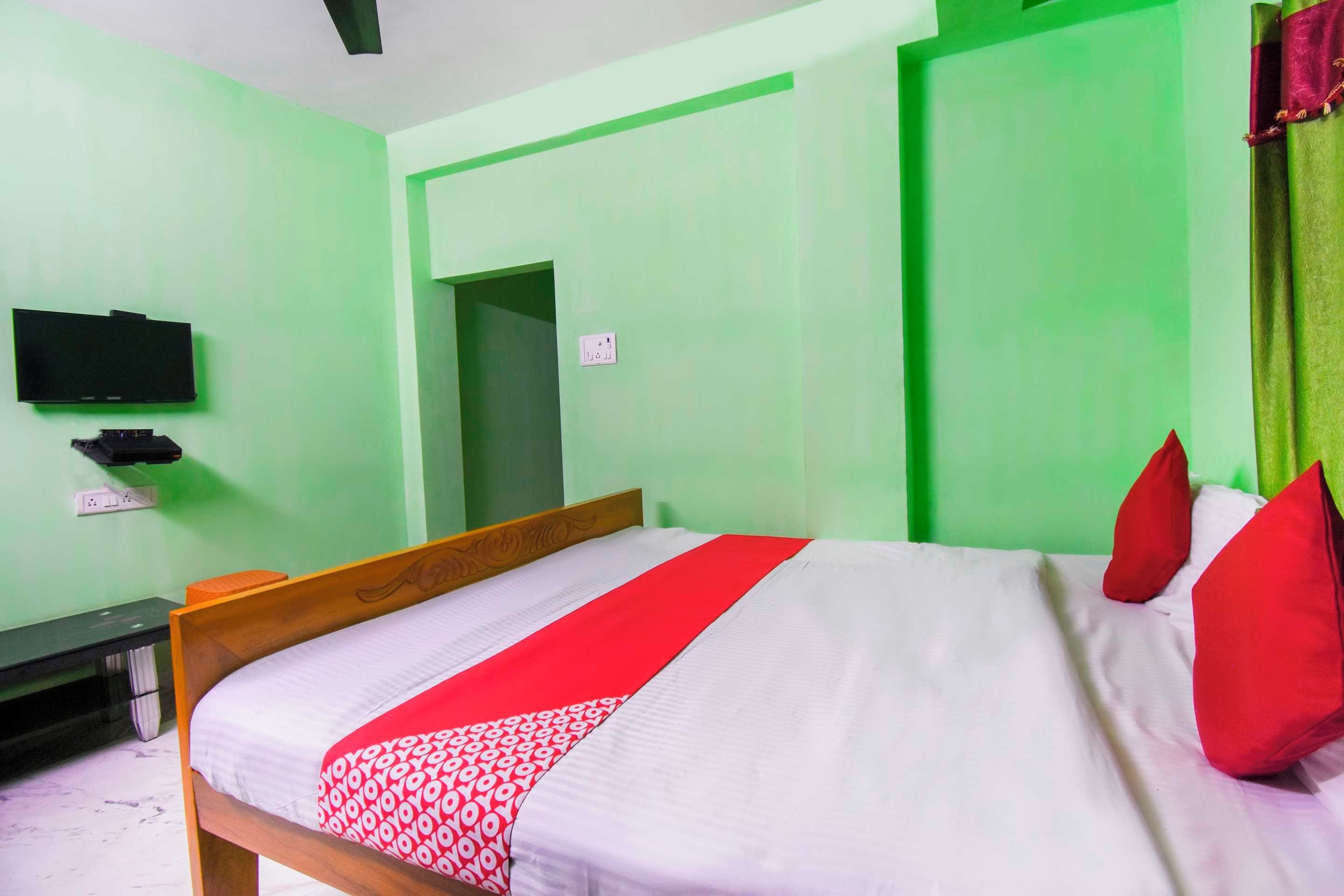 A room with a bed, a television on the wall, and a door.