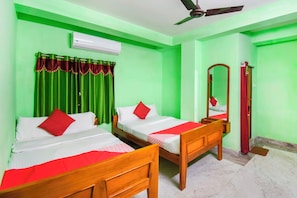 A hotel room with two wooden beds, green walls, a ceiling fan, an air conditioning unit, and a mirror. - Collection O Kolkata Jagannath Temple (Kolkata)