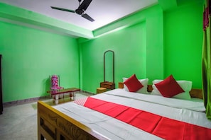 A bedroom with a bed, a chair, a nightstand, a mirror, and a ceiling fan. - Collection O Kolkata Jagannath Temple (Kolkata)