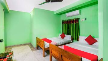 Una habitación con dos camas, ventilador de techo, aire acondicionado y una pared verde.