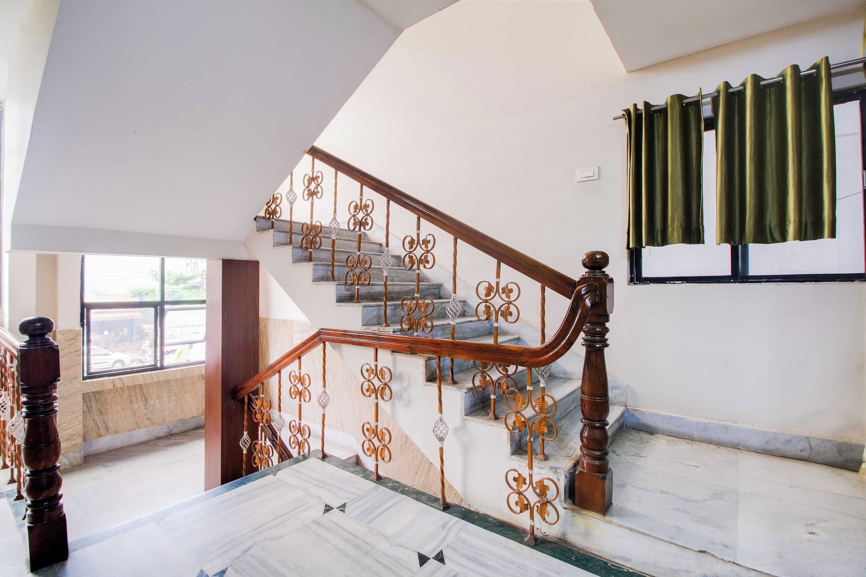 Una escalera con barandales metálicos decorativos y una barandilla de madera, que conduce a un piso superior.