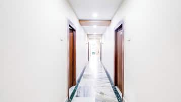 Un pasillo de hotel con suelo de mármol, puertas de madera e iluminación empotrada en el techo.