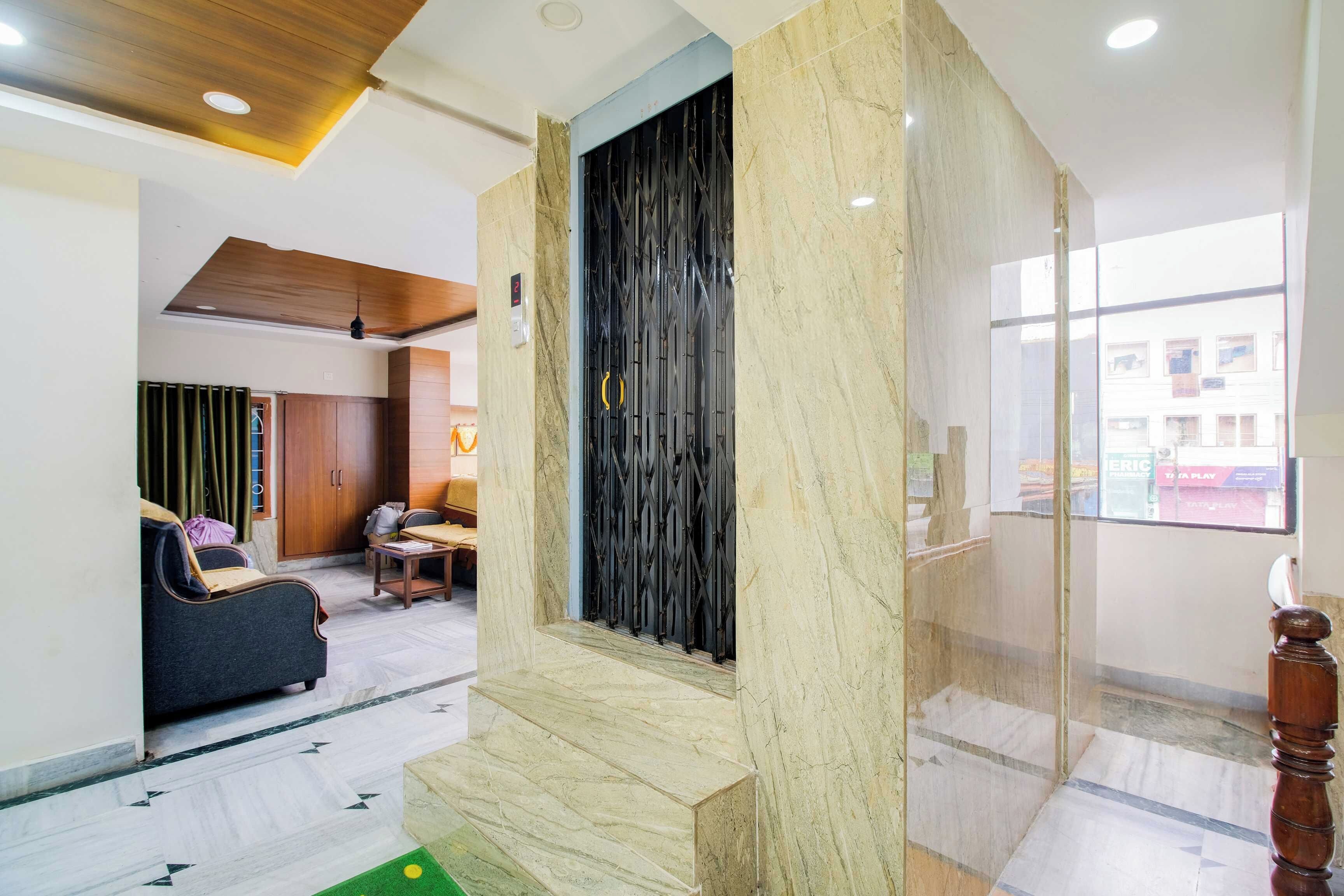 A hotel lobby with a marble column, a black metal gate, and a seating area with a sofa and chairs.