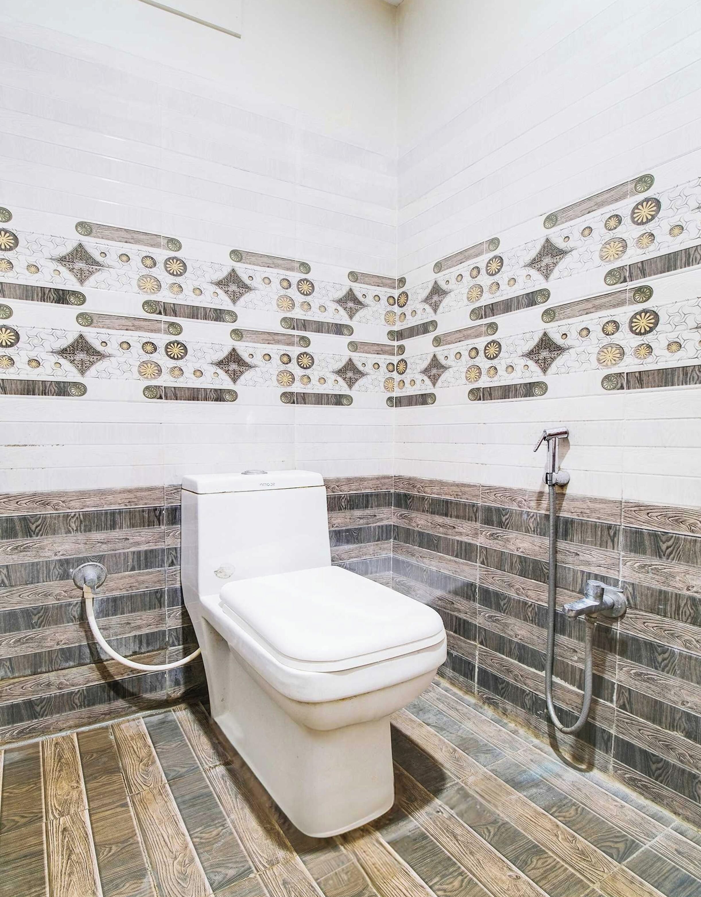 A bathroom with a toilet, shower, and decorative tiled walls.