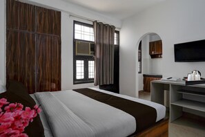 A hotel room with a bed, a desk, a TV, and a window with curtains. - Hotel O Sector 23 Udyog Vihar (Gurugram)