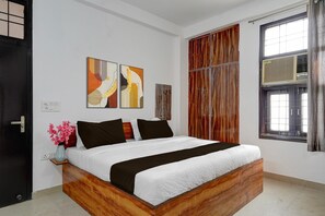 A bedroom with a wooden bed, a window with curtains, and abstract wall art. - Hotel O Sector 23 Udyog Vihar (Gurugram)