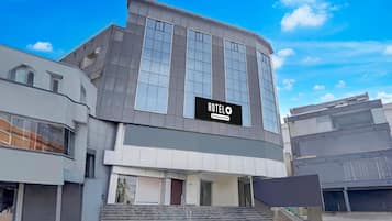 A modern hotel building with a prominent sign, a staircase leading to the entrance, and a clear sky.