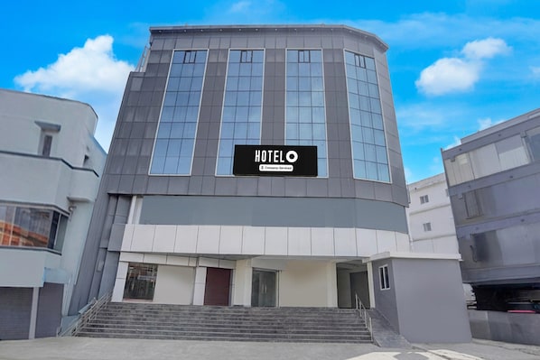 A modern hotel building with a prominent 'HOTEL O' sign, a curved facade, and a staircase leading to the entrance. - Hotel O Magunta Layout Nellore (Nellore)