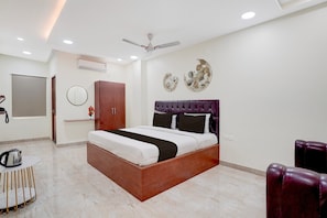 A modern bedroom with a wooden bed, a ceiling fan, a round mirror, and decorative wall art. - Hotel O Magunta Layout Nellore (Nellore)