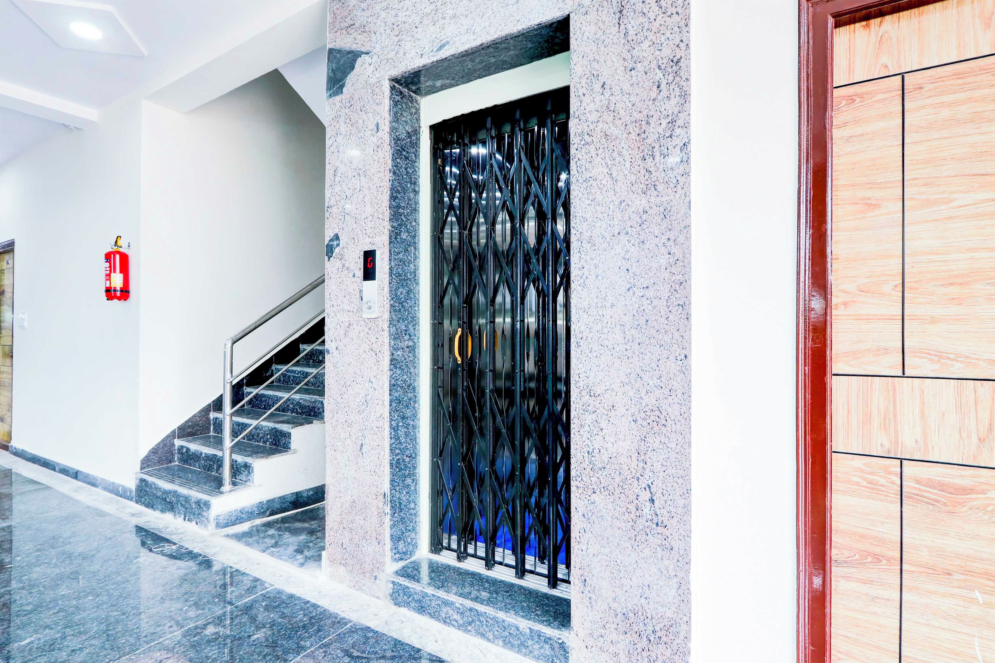 A modern interior with a staircase, a fire extinguisher, and a metal gate.