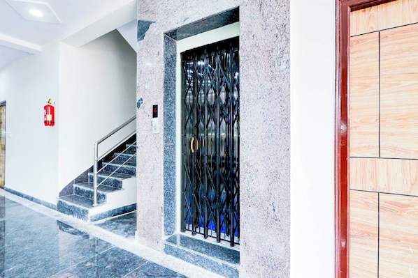 Un interior moderno con una escalera, un extintor y una reja de metal.