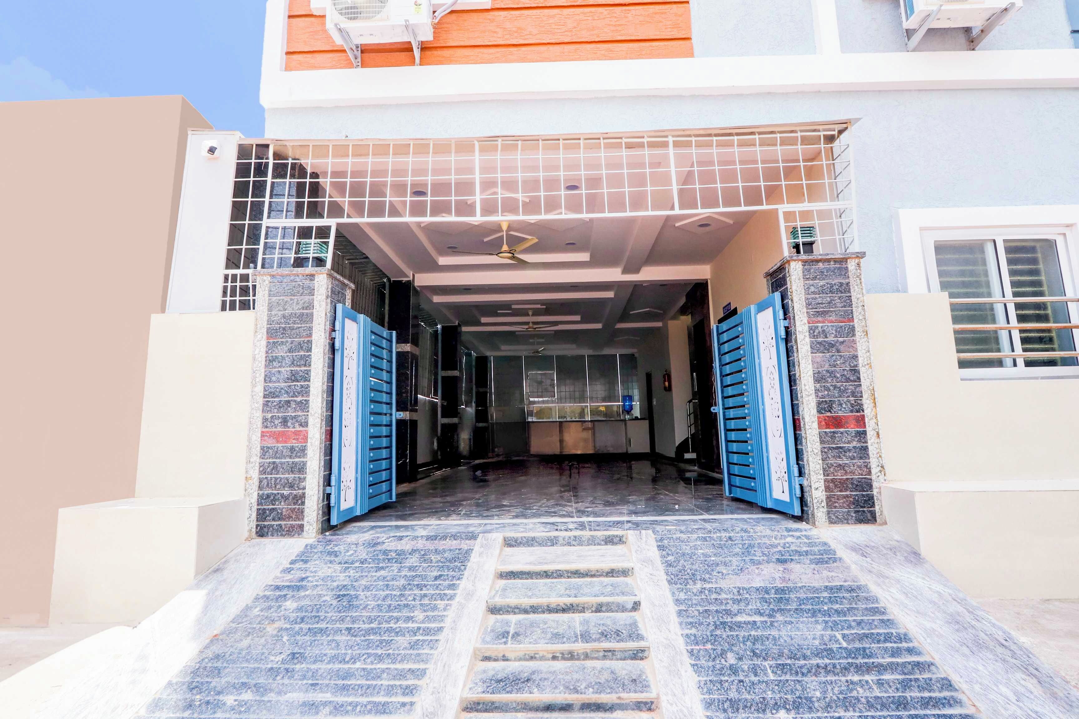 Entrada de un edificio con tejado de azulejos, una escalera que sube y dos puertas azules.