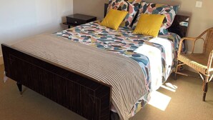 A bedroom with a bed, nightstands, a chair, and wall-mounted lights. - Vrbo Property (Deux-Grosnes)