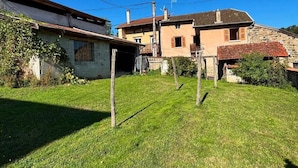 A residential area with a grassy yard, a stone building, and a wooden fence. - Vrbo Property (Deux-Grosnes)