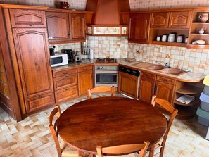 A kitchen with wooden cabinets, a round dining table, and a tiled backsplash.