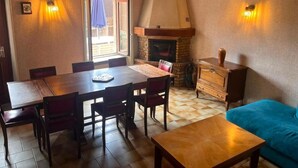 A dining area with a wooden table and chairs, a fireplace, and a sofa. - Vrbo Property (Deux-Grosnes)