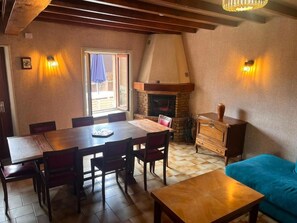Een eetgedeelte met een houten tafel, stoelen, een open haard en een bank.
