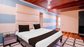 A modern bedroom with a bed, a nightstand, a ceiling fan, and a wooden floor. - Collection O Khoni Taloja Bypass (Mumbai)