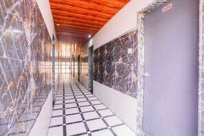 A hallway with a checkered floor, marble walls, and a wooden ceiling. - Collection O Khoni Taloja Bypass (Kalyan)