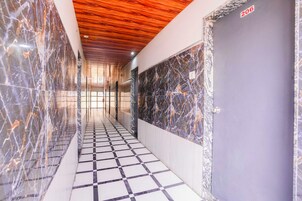 A hallway with a checkered floor, marble walls, and a wooden ceiling.