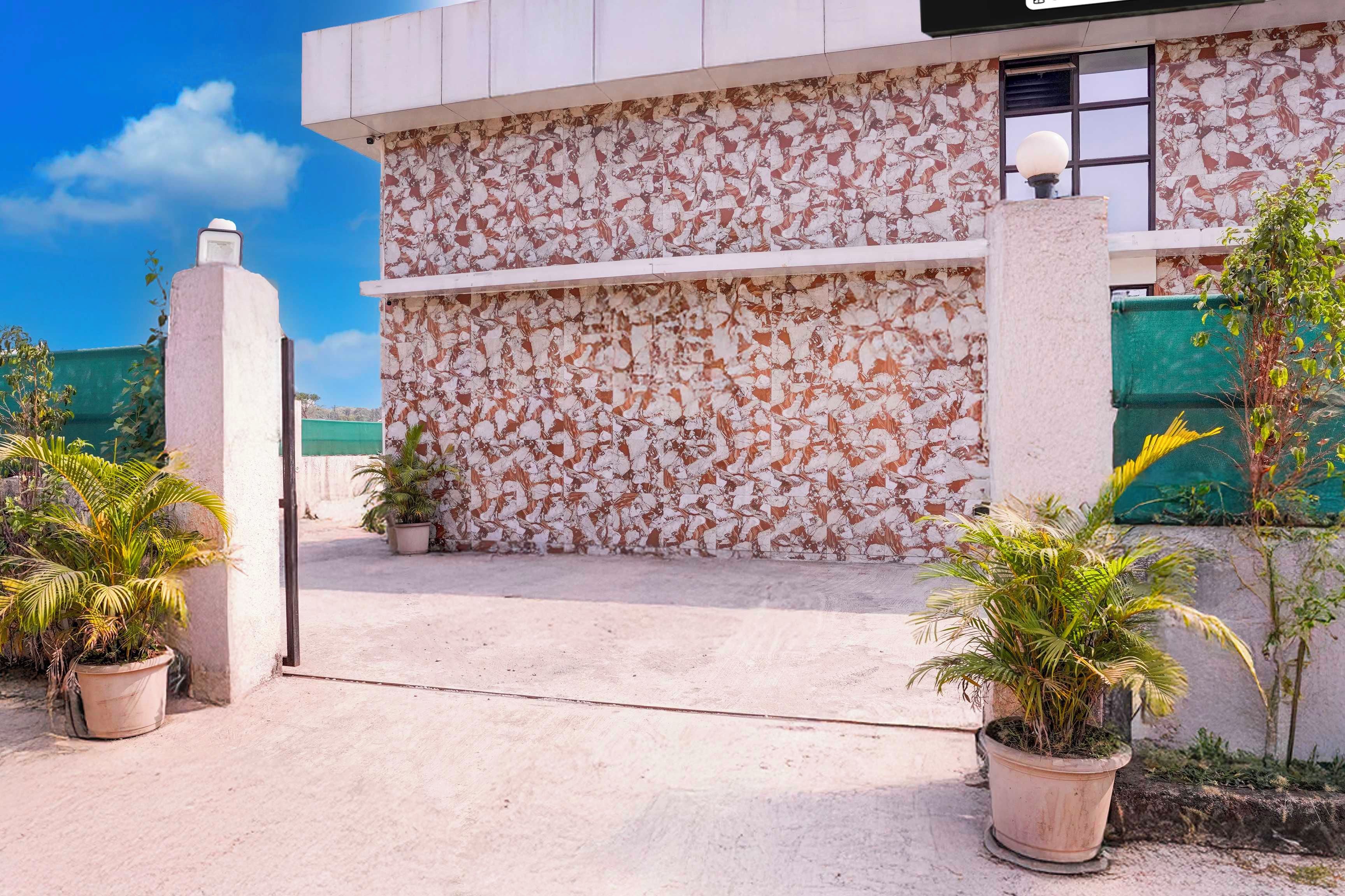 Un edificio con fachada texturizada, entrada protegida por una reja y plantas en macetas.